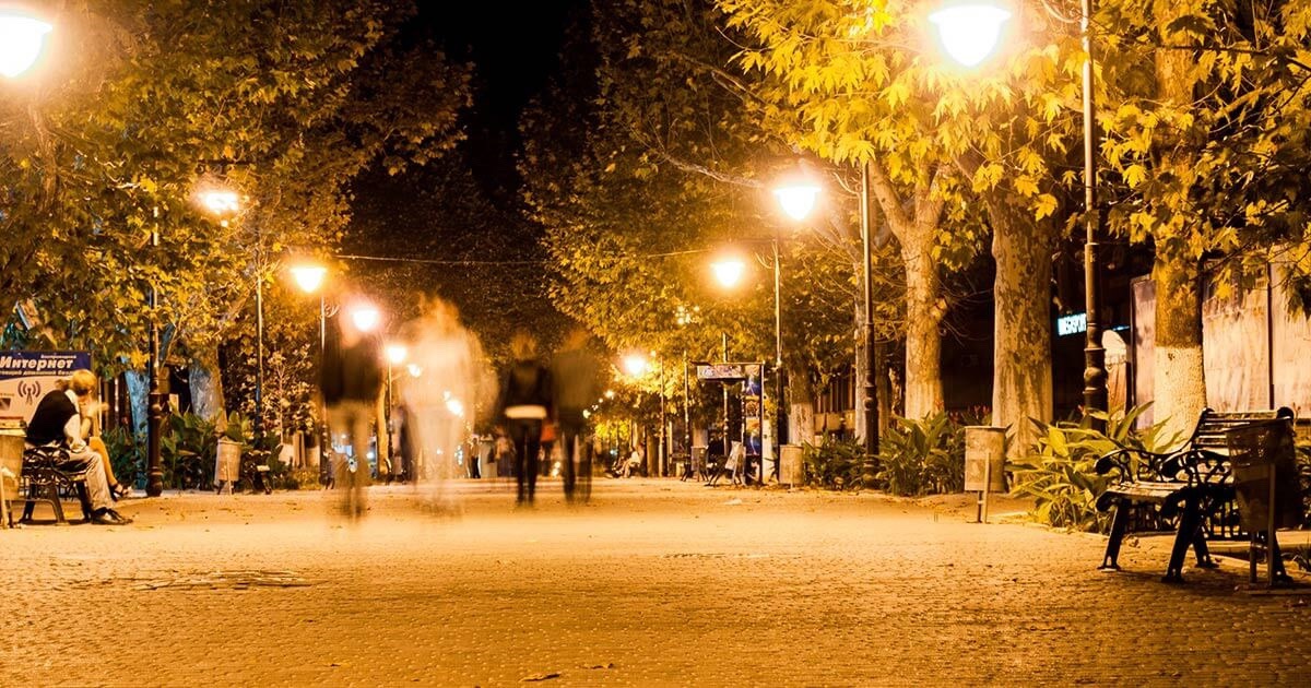 люди йдуть по вечірній вулиці з ліхтарями