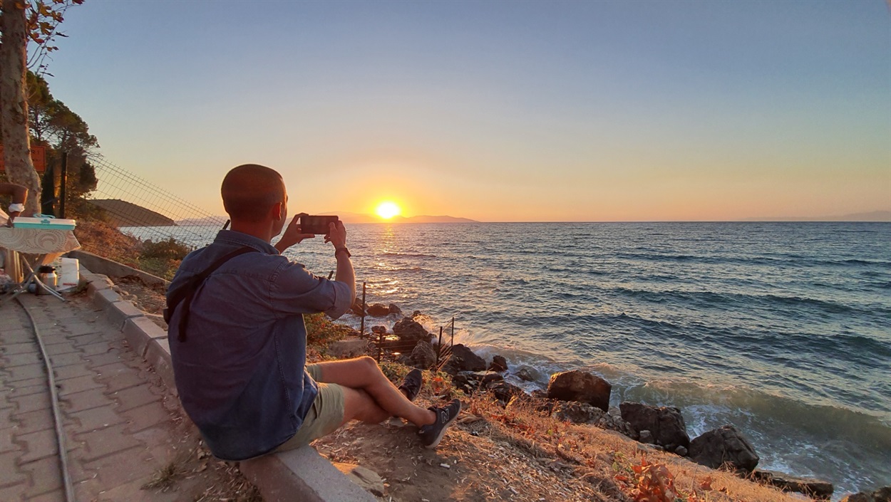 хлопець фотографує захід сонця на морі