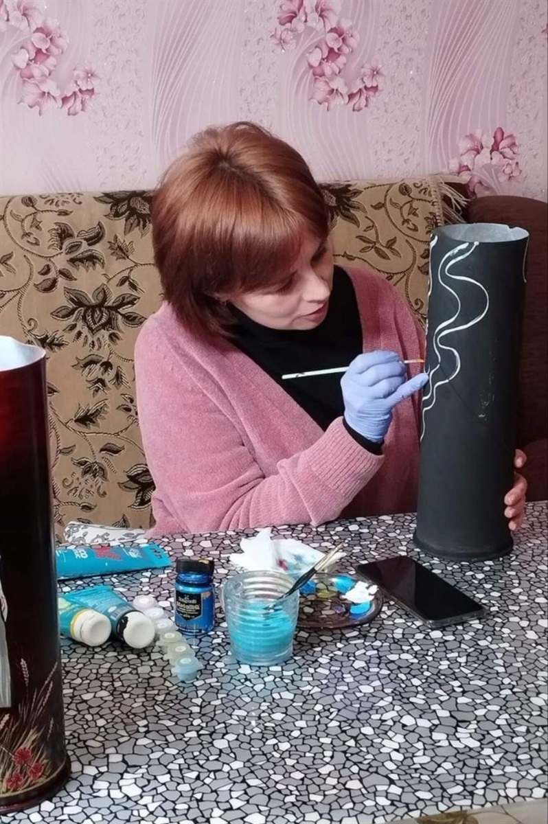 Художниця розписує тубус від снаряда